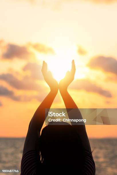 Summer Sun June Solstice Concept And Silhouette Of Happy Young Womans Hands Relaxing Meditating And Holding Sunset Against Warm Golden Hour Sky On The Beach With Natural Ocean Or Sea Background Stock Photo - Download Image Now