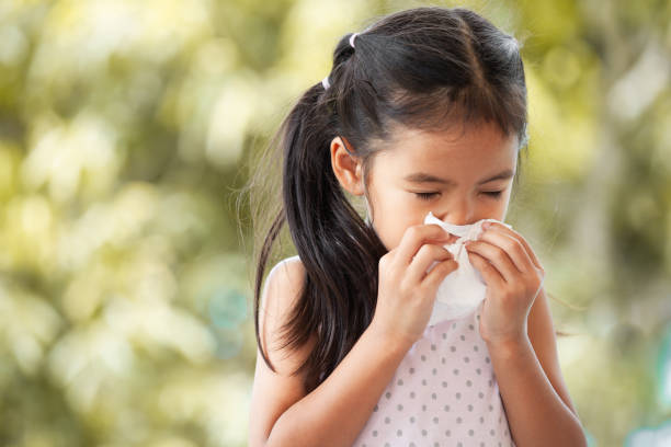 sick asian little child girl wiping and cleaning nose with tissue on her hand - allergy sneezing cold and flu flu virus imagens e fotografias de stock