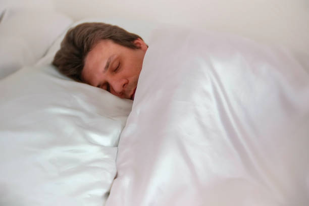 istock Man is sleeping in bed alone under the blanket. Side view. 980534930