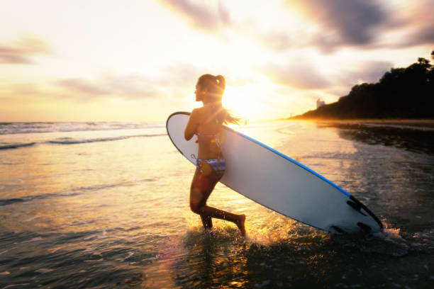Young girl soaking in the sun while floating on a surfboard in the ocean