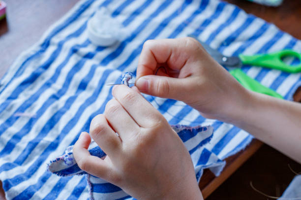 i primi passi della ragazza nel padroneggiare il cucito. ago con filo nelle mani del bambino - embroidery cross stitch needle sewing foto e immagini stock