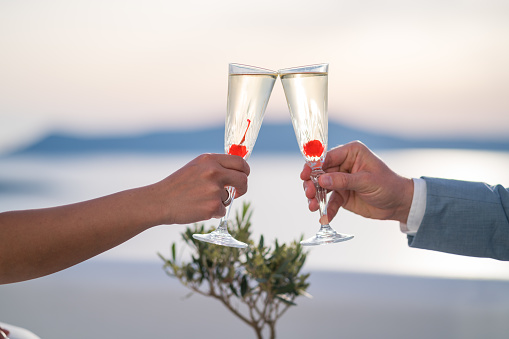 detail hand of woman and man toasting with champagne glasses high above sea late afternoon
