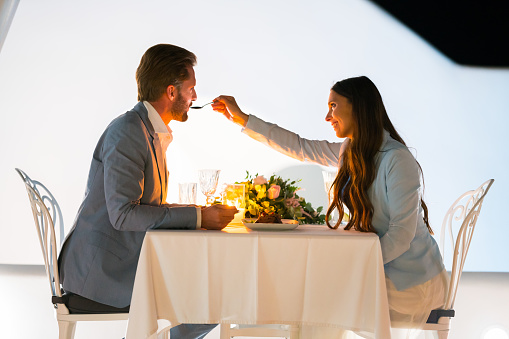 couple in love feeding each other with the dessert at candlelight dinner honeymoon, date, dating