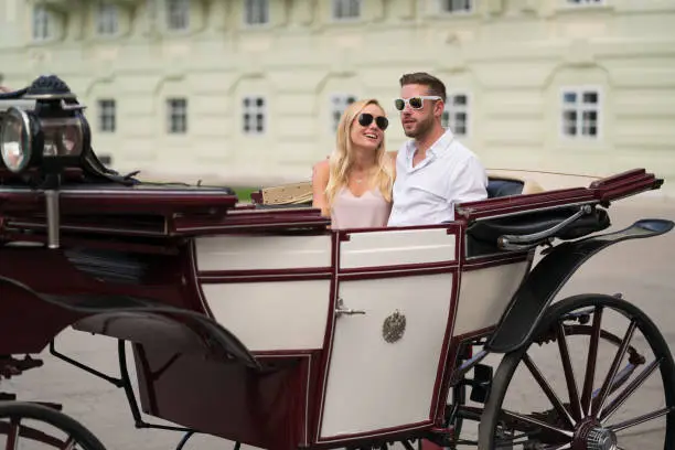 young tourist couple with sunglasses in fiaker during summer city vacations in vienna