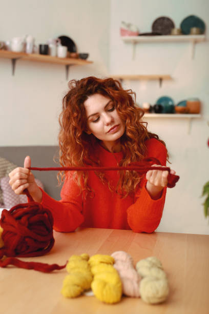 istock Ginger-haired girl wearing red sweater holding crochet thread 980595912