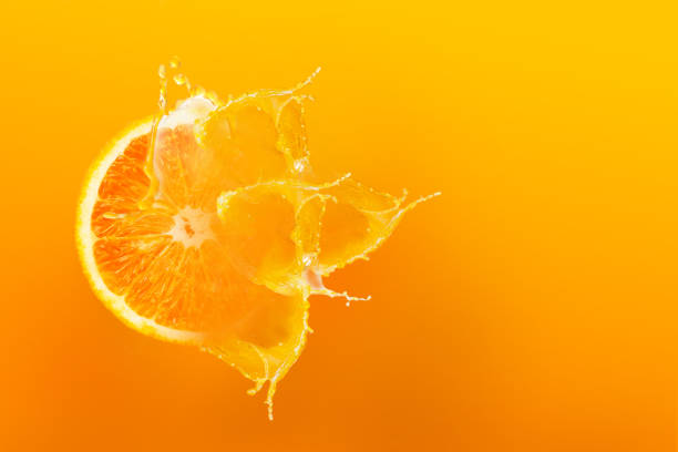 istock Fresh half slice of ripe orange fruit floating with splash drop on orange juice with copy space over orange background 980608334