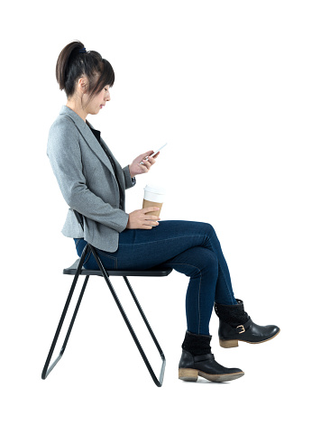 Businesswoman sitting on chair and using phone.