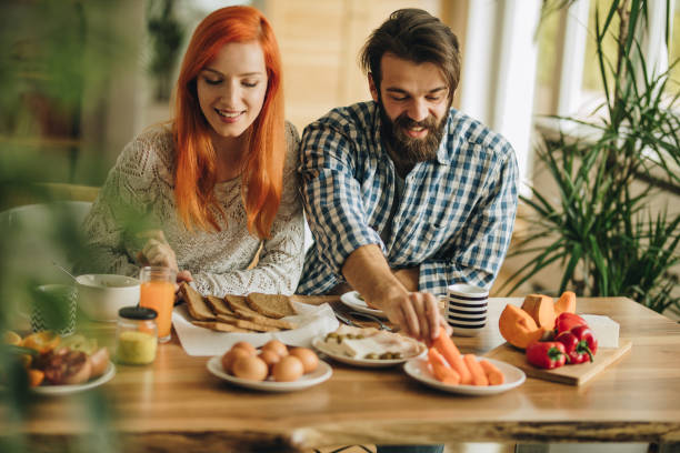 istock Young couple sitting at dining table while having breakfast in the morning. 980618712