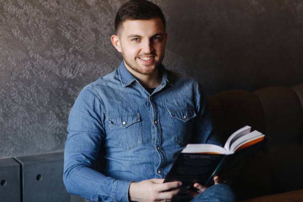 istock Handsome man with a beard reading a book in a cafe 980620030