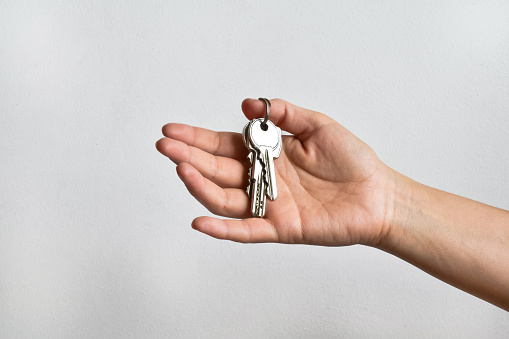 Hand (female) with a bunch of keys on white wall background