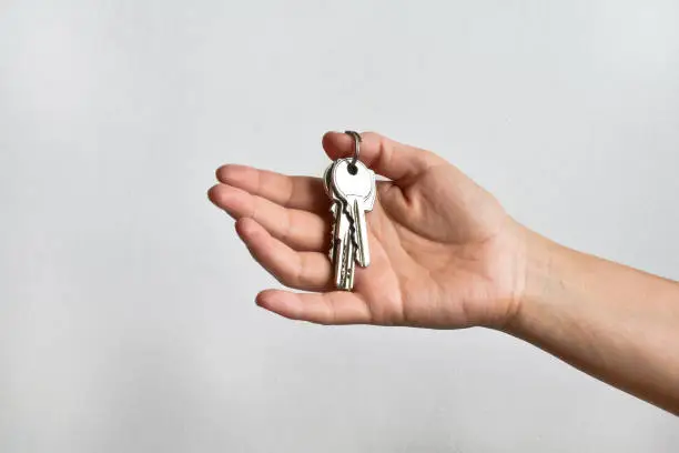 Hand (female) with a bunch of keys on white wall background