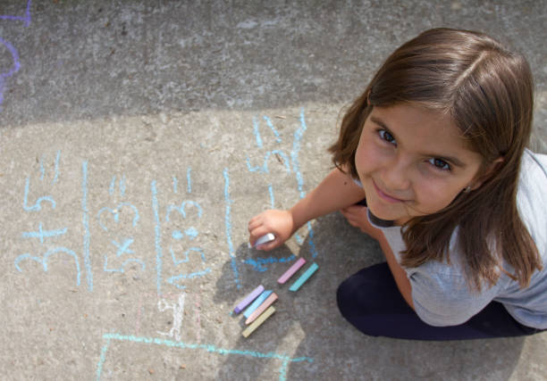 chico chica pensar, escribir y contar con ecuaciones matemáticas con tizas de colores sobre un pavimento. concepto de escuela y de las vacaciones. concepto de educación. - little girls sidewalk child chalk fotografías e imágenes de stock