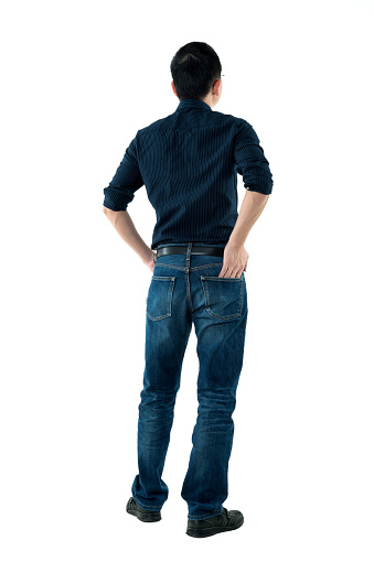 Rear view of man standing with hands in pockets.