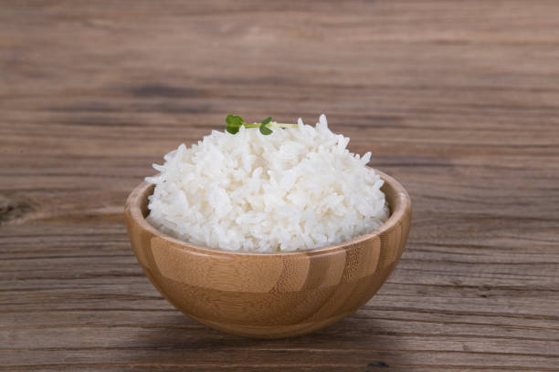 Uma tigela de madeira de arroz cozido na velha mesa de madeira - foto de acervo