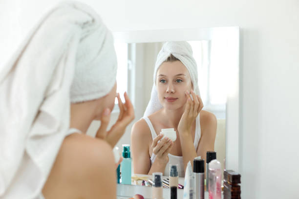 istock Young woman applying moisturizer on face 980633452