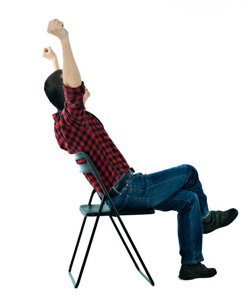 Man sitting on chair with arms raised.