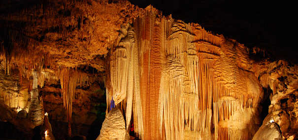 Karst cave, amazing view of stalactites and stalagnites in colorful bright light, beautiful natural landmark in touristic place.