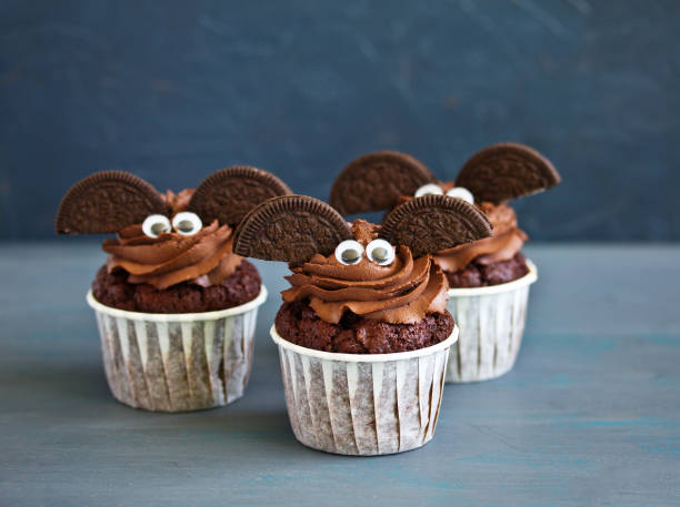 muffins au chocolat, avec une crème au chocolat en forme de chauve-souris sur halloween. - baked cheese topping photos et images de collection