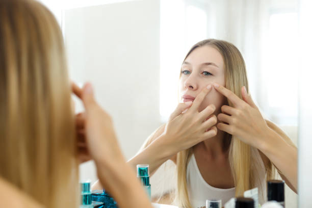 istock Young beautiful woman squeezing pimples on her face 980639976