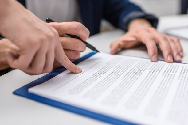 istock cropped shot of client signing contract while manageress pointing at it 980643930