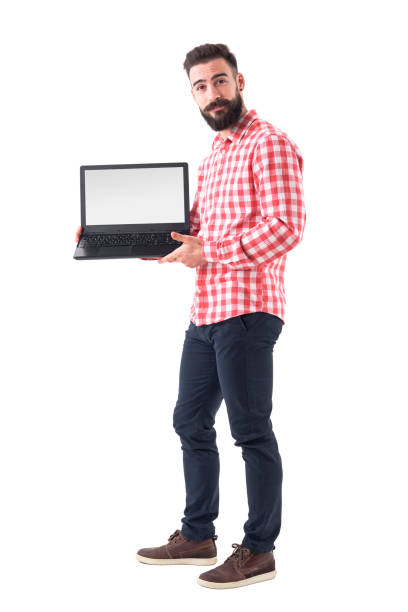 Cool bearded hipster guy in smart casual clothes showing blank laptop monitor. stock photo