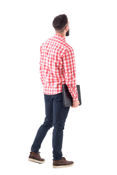 Back view of smart casual man with laptop walking and looking up watching copyspace