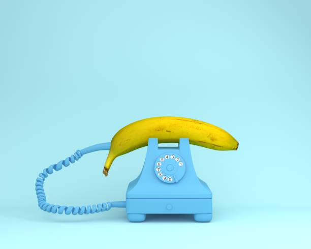 одноместный банан против синего ретро-телефона на голубоватом фоне. фруктовая минимальная концепция. - retro revival traditional photography classic equipment стоковые фото и изображения