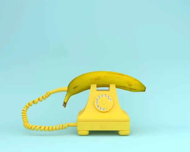 Creative idea layout fresh banana with yellow retro telephone on bluish background.  Fruit minimal concept.