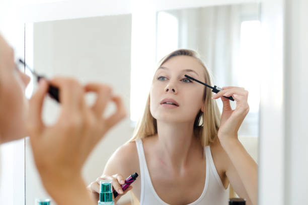 istock Young woman putting on mascara 980650646