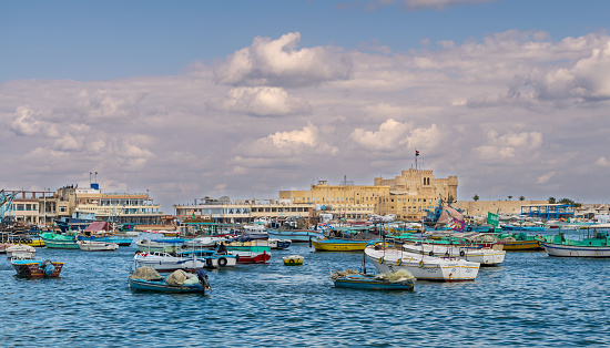 Alexandria: Old east harbor of Alexandria city at the Mediterranean Sea with fishing boats in the foreground and the Citadel of Qaitbay in the background in a cloudy winter day, Egypt