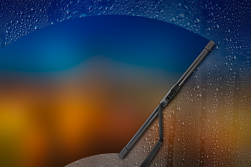 Car wiper cleaning rain drop on glass with color background
