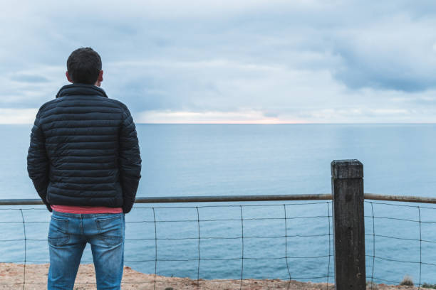 istock Man looking at view of sunset and clouds over ocean 980667334
