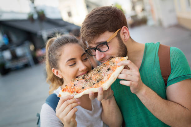 istock Happy couple sharing pizza on street 980667898