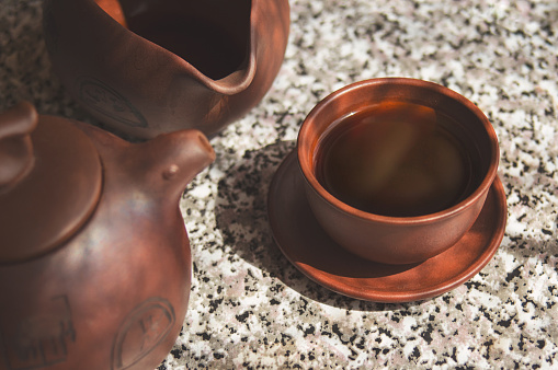 Black Chinese Puer tea brewed in a clay cup. Composition of ceramic ware for tea ceremony.