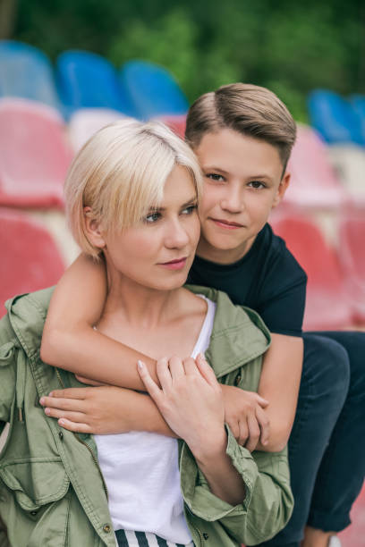 istock beautiful happy mother and son hugging while sitting together in stadium 980689240