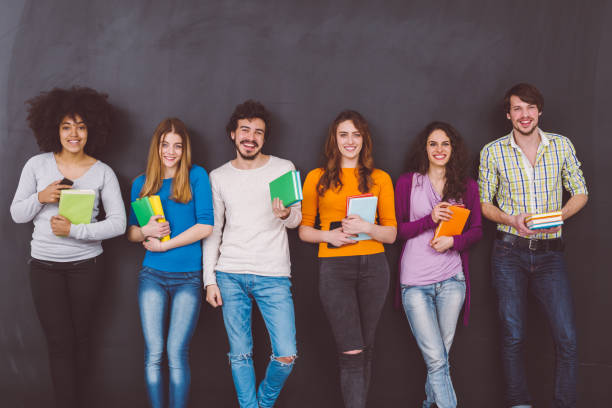 istock Classmates with textbooks standing against blackboard 980697750