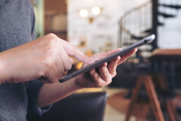 istock Closeup image of hands holding , using and touching a tablet pc in modern cafe 980698988