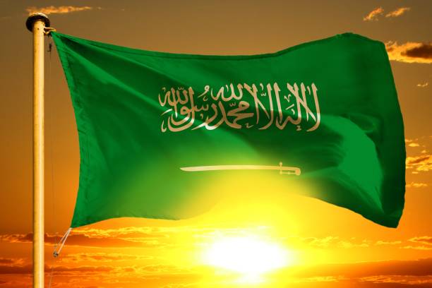 istock Saudi Arabia flag weaving on the beautiful orange sunset with clouds background 980711636