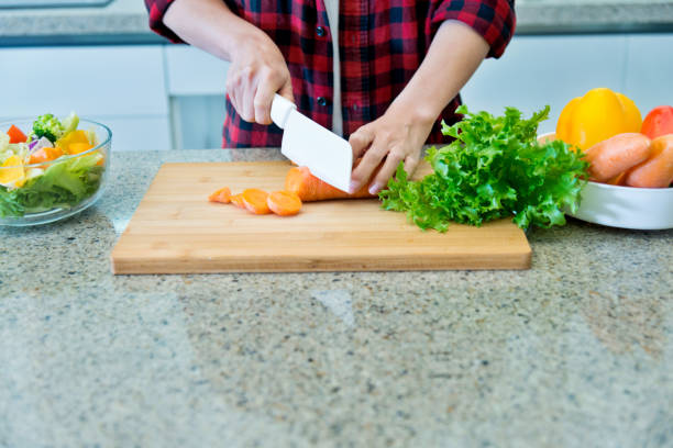istock Woman cutting carrot on board in kitchen 980719796