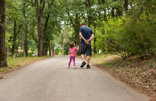 istock Father And Daughter Walking Through Woods at Park 980719862