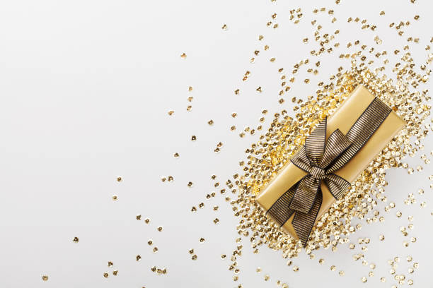 istock Gift or present box decorated golden sequins on table top view. Flat lay for Christmas or birthday. 980725228