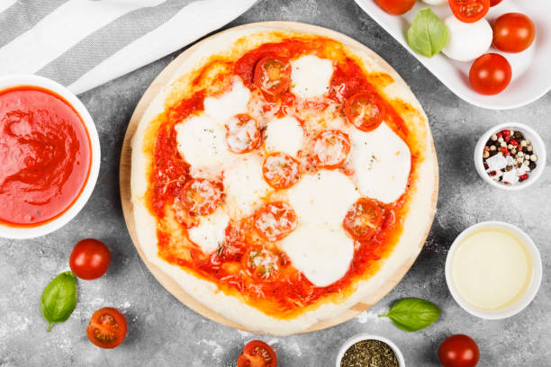 istock Pizza with cheese, tomatoes and basil on  gray background. Top view. Food background 980732996