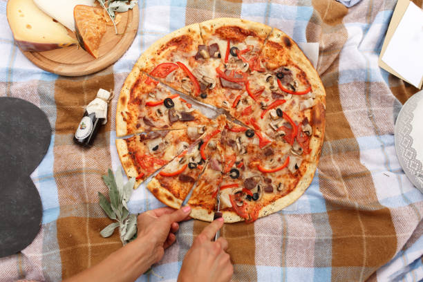 cut pizza at a picnic in sunday park