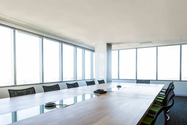 Interior of empty brightly board room in a financial institution. Interior of board room. Conference phone is on table. Windows are in a row at bright daylight modern office. Financial companies board of directors room. shareholders meeting stock pictures, royalty-free photos & images