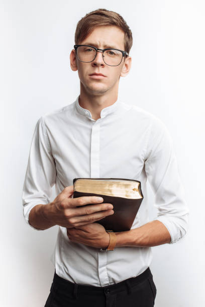 istock Man reading Bible, white background, book in hand close-up 980772558