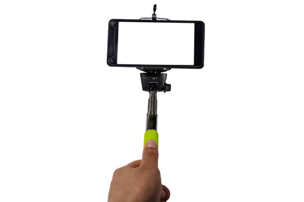 istock Human hand holding monopod for selfie with smartphone isolated on white background 980772660