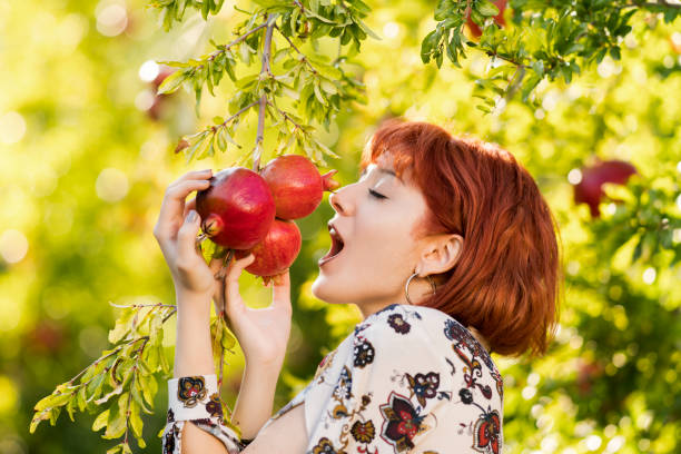 istock Young beautiful girl with pomegranate trees 980781084