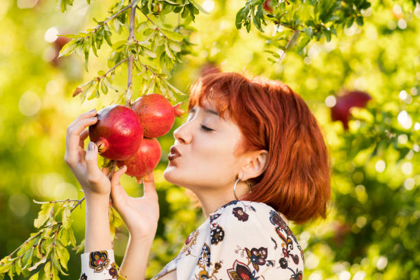 istock Young beautiful girl with pomegranate trees 980782326