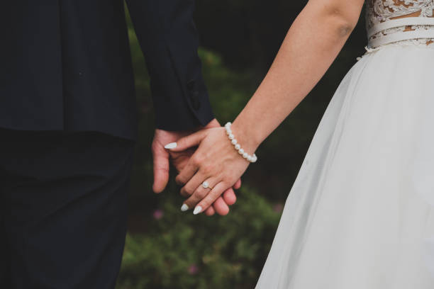Young married couple holding hands Young married couple holding hands bracelet photos stock pictures, royalty-free photos & images
