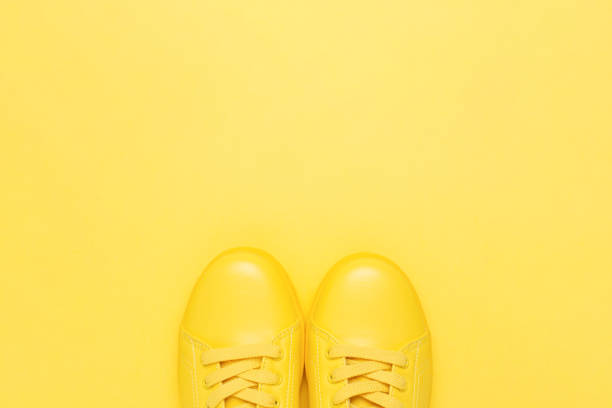 Pair of yellow shoes on yellow background. Pair of yellow shoes on yellow background. Trendy summer color, monochrome image. Hipster concept. yellow shoes stock pictures, royalty-free photos & images